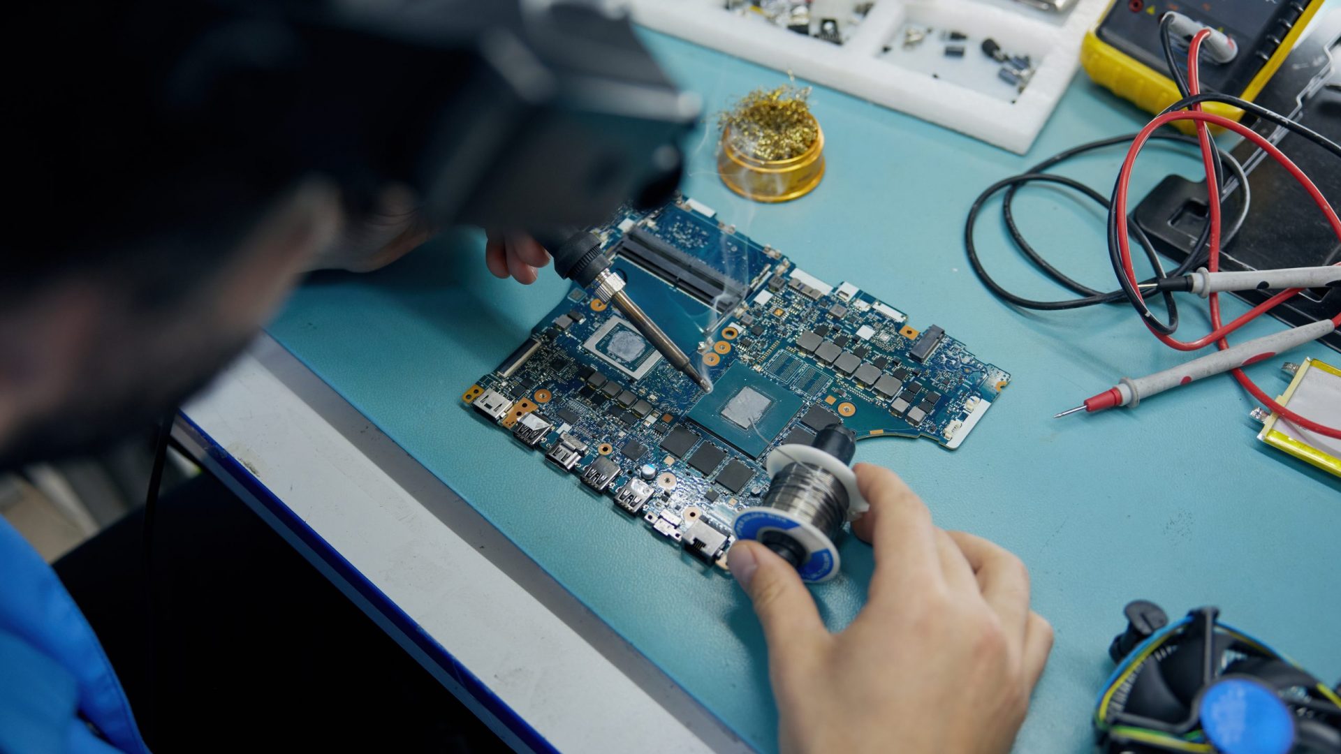An individual is working on a motherboard in a lab A man is diligently working on a specialized motherboard, focusing on intricate electronic components