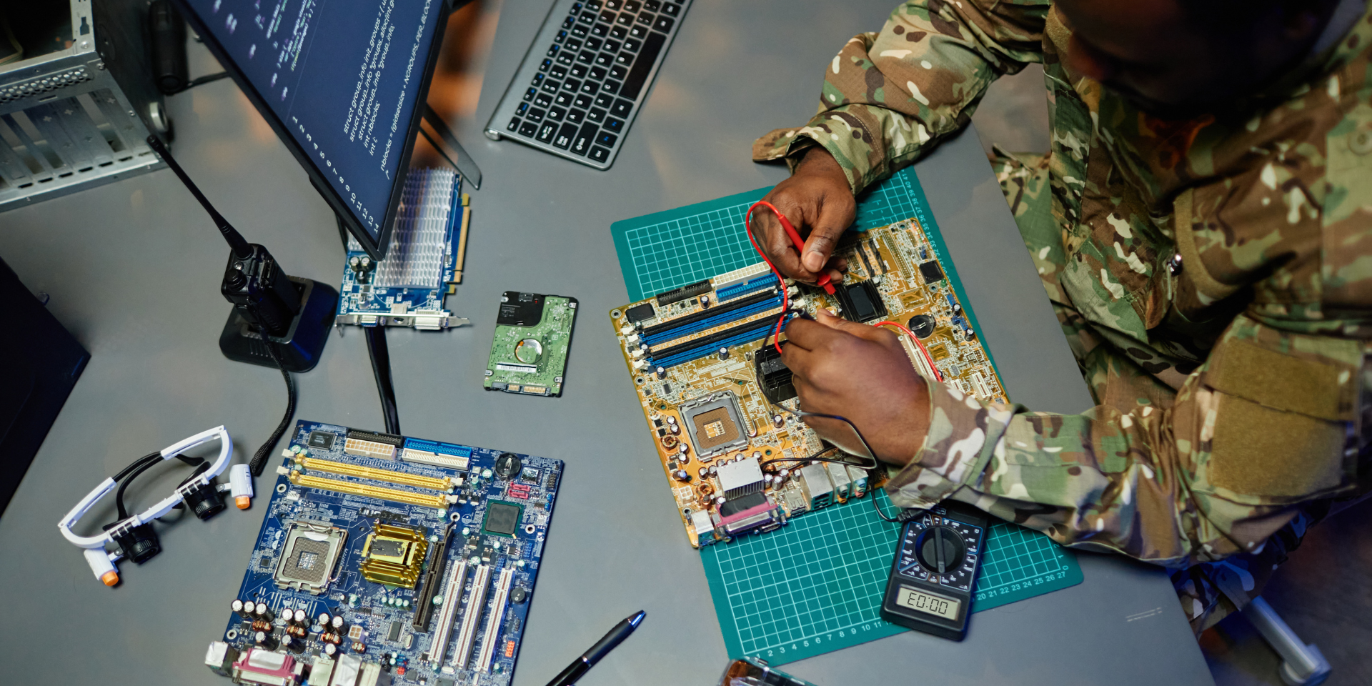 Above angle of young man in military uniform repairing motherboard
